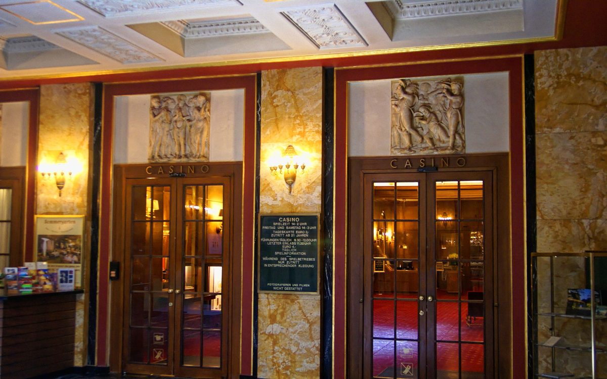 Eingangshalle im Kurhaus mit zwei Glastüren mit der Aufschrift Casino, Reliefs darüber und vergoldeten Zierleisten