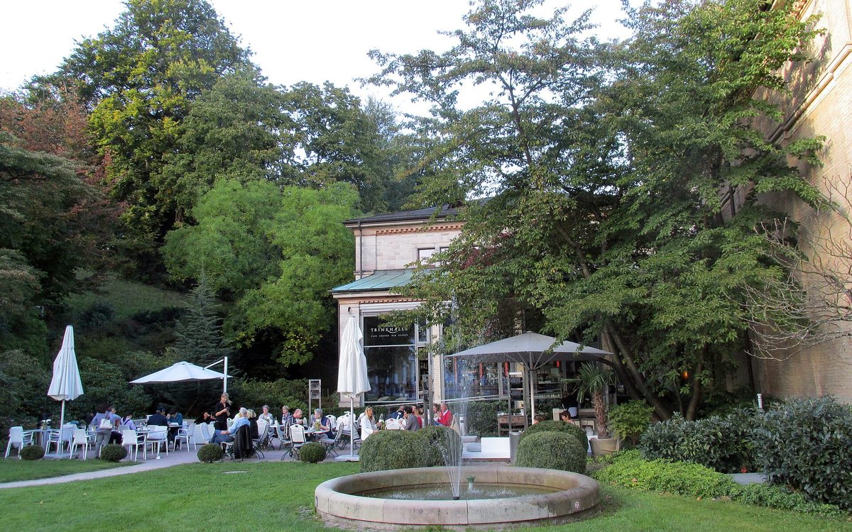 Café-Terrasse mit weißen Stühlen und einem Brunnen an der Trinkhalle im Baden-Badener Kurgarten